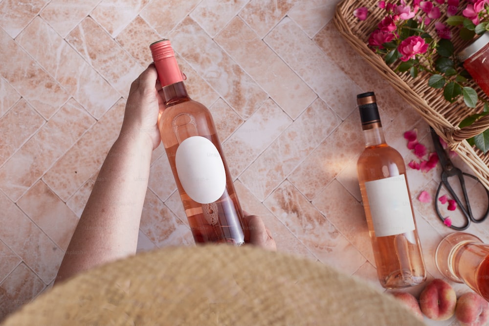 uma pessoa segurando uma garrafa de vinho ao lado de uma cesta de flores