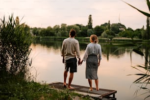 a man and a woman standing on a dock looking at the water