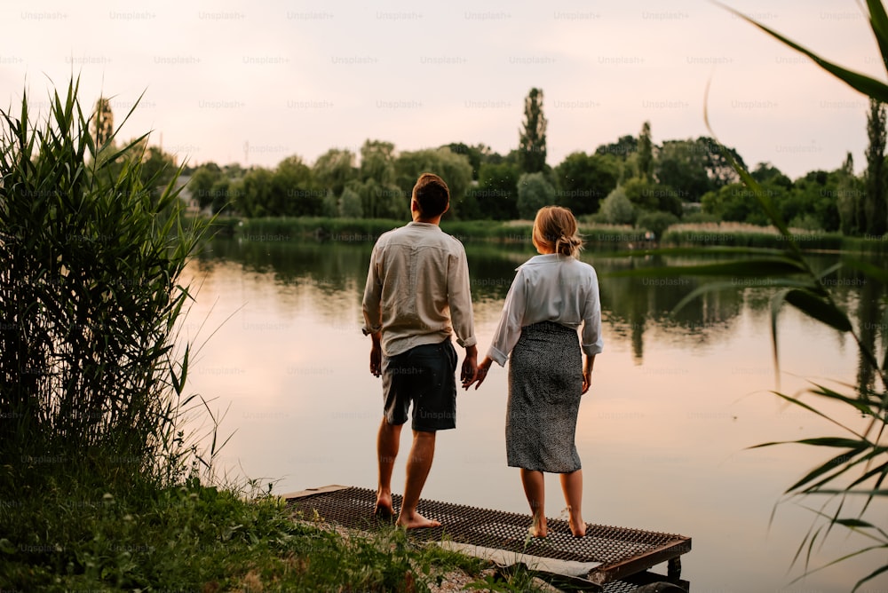 a man and a woman standing on a dock looking at the water