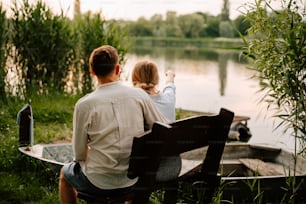 a man and a woman sitting on a bench by a lake