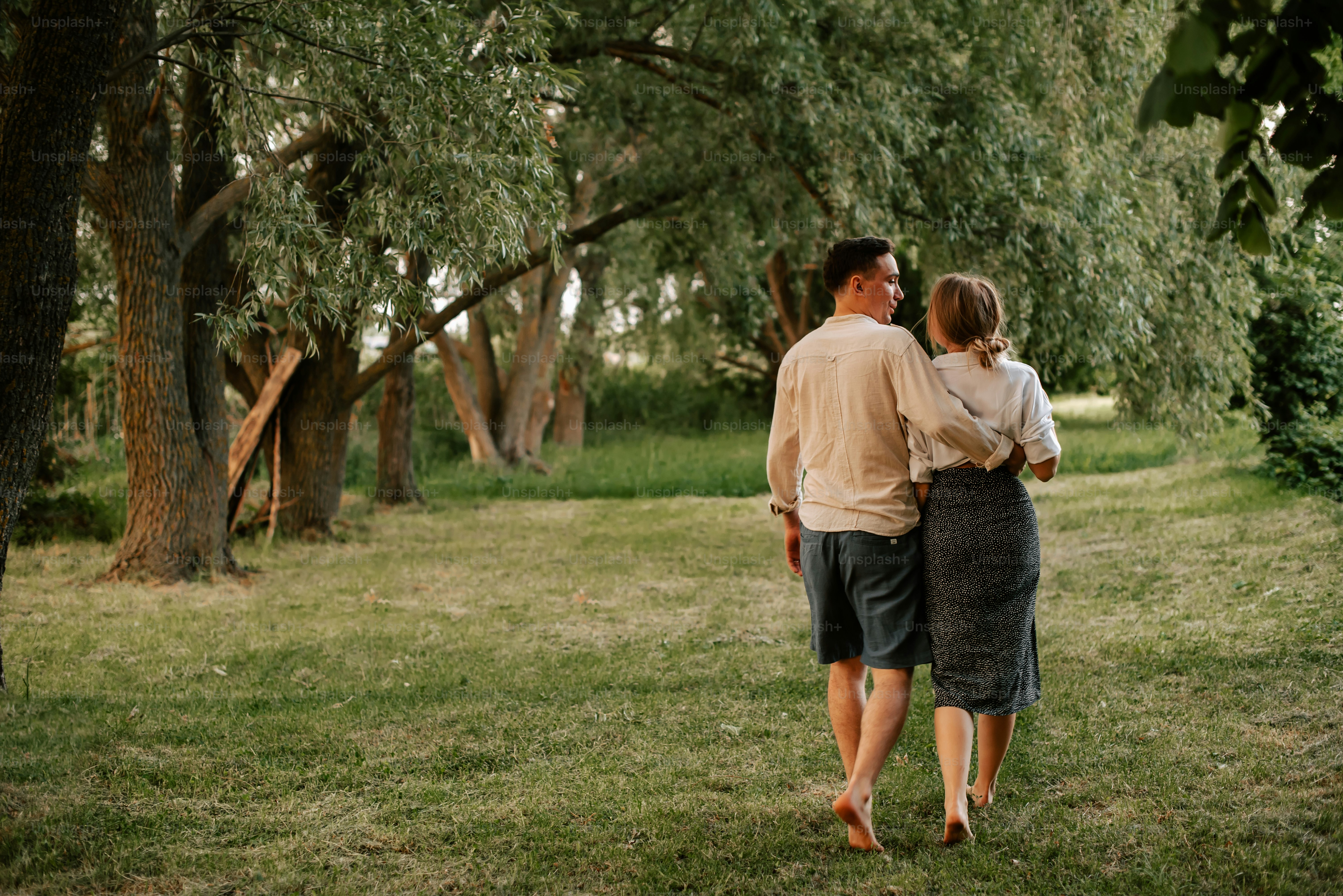 a man and a woman walking through a park