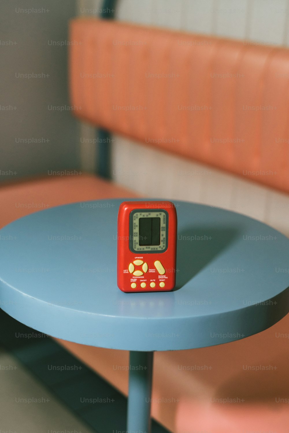 eine kleine rote Uhr, die auf einem blauen Tisch sitzt