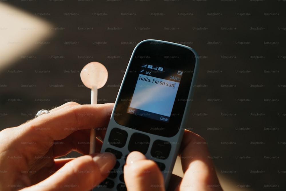 a person is holding a cell phone with a toothbrush in their hand