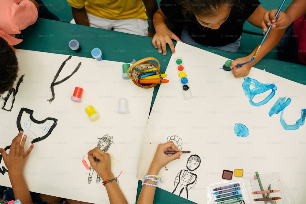 un gruppo di bambini seduti a un tavolo che disegnano su carta