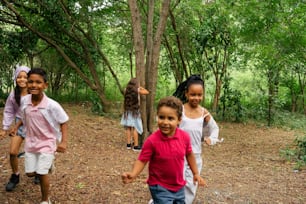 a group of young children running through a forest