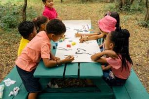 eine gruppe von kindern, die an einem picknicktisch sitzen