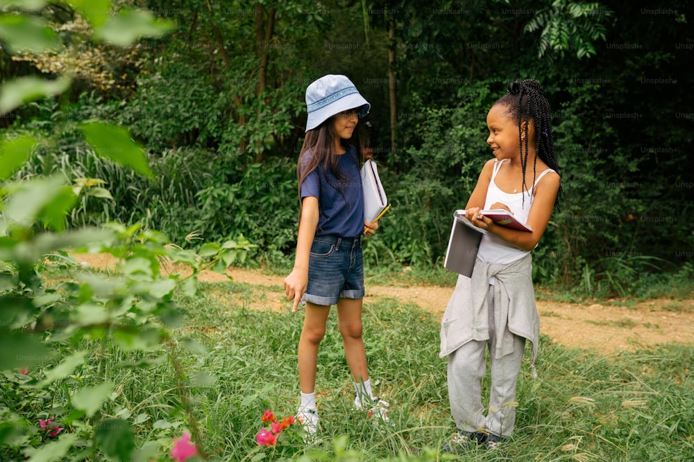 two young girls are standing in a field