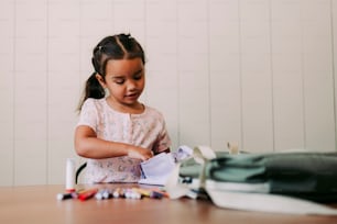 a little girl sitting at a table with a piece of paper