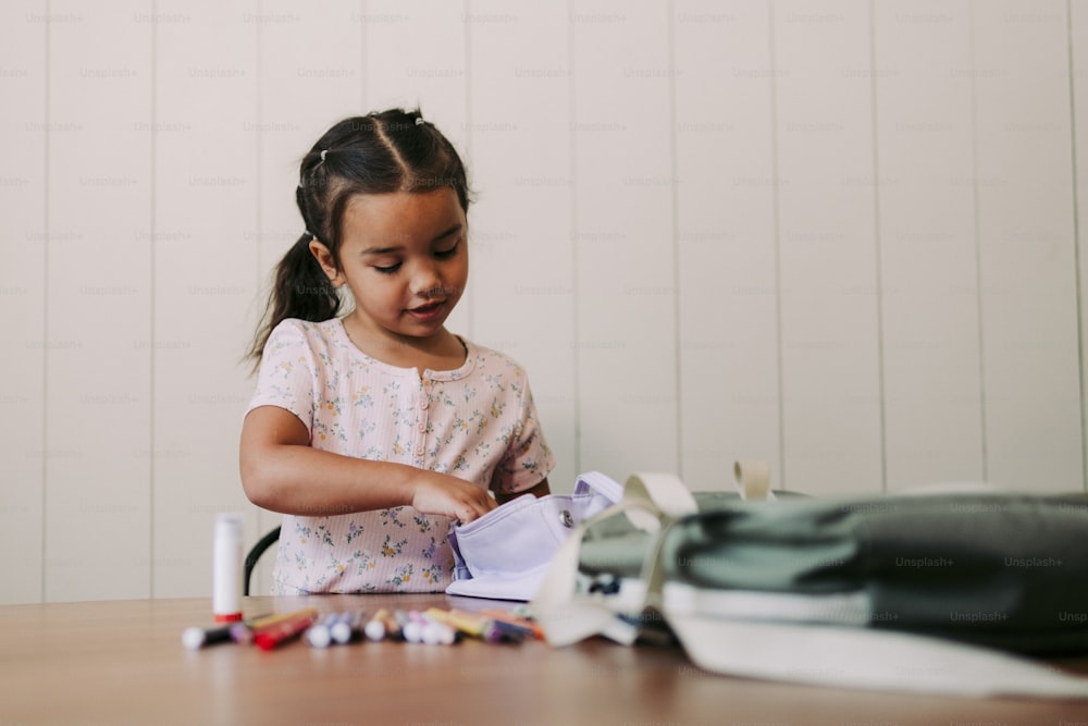ein kleines Mädchen, das mit einem Blatt Papier an einem Tisch sitzt