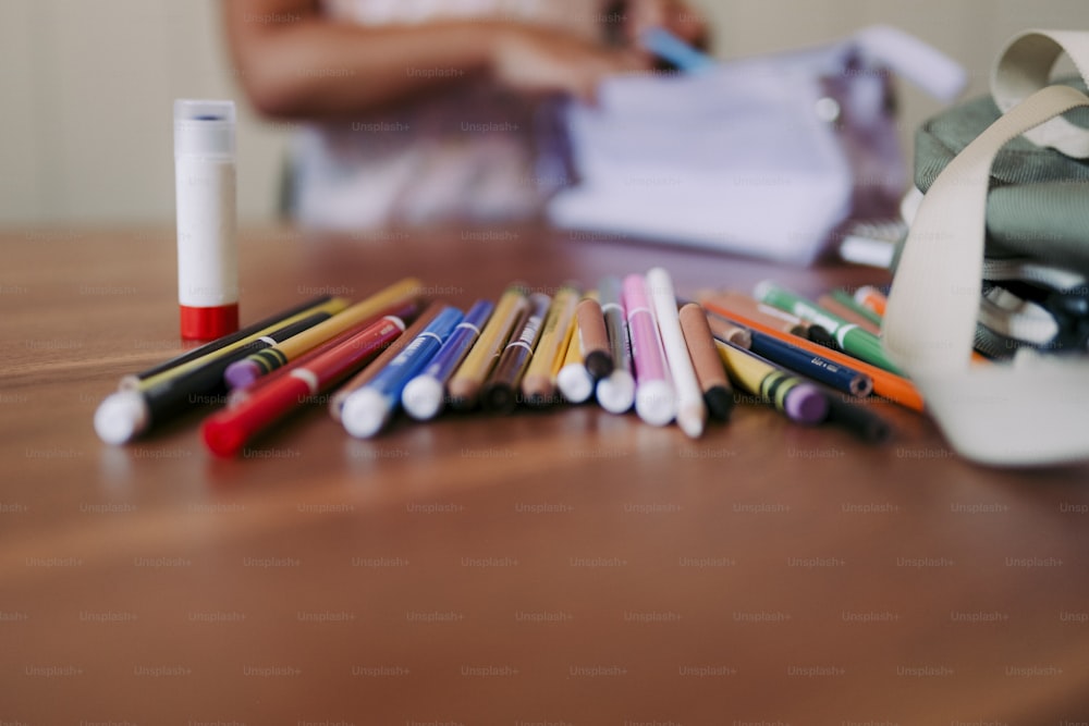 une table en bois surmontée de nombreux crayons de différentes couleurs