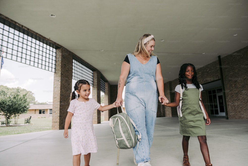 a woman and two little girls holding hands