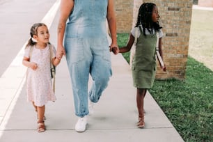 a woman and two children walking down a sidewalk
