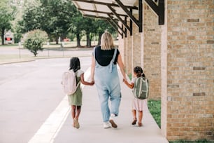 a woman and two girls walking down a sidewalk