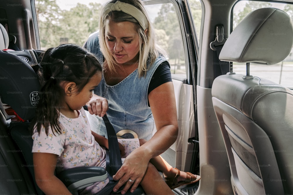 a woman and a little girl in a car seat
