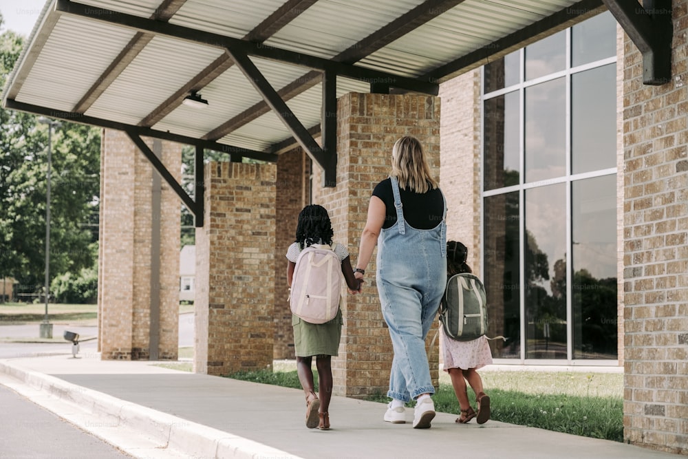 a woman and two young girls walking down a sidewalk