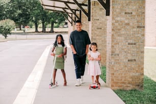 a man and two little girls are walking down the sidewalk