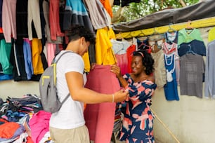 a man and a woman looking at clothes on a rack