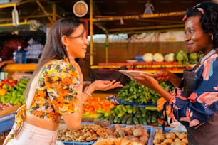 two women standing in front of a produce stand