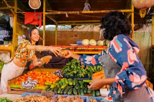 Un couple de femmes qui se tiennent devant des légumes