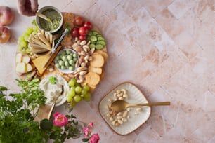 a platter of cheese, crackers, grapes, nuts and vegetables