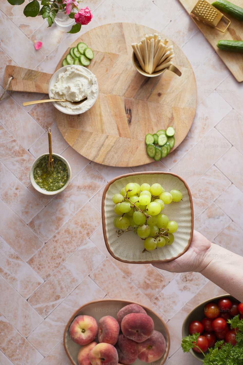 a person holding a plate of fruit on a table