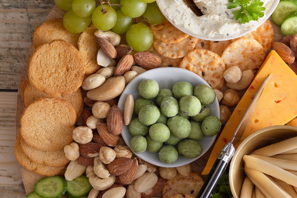 a platter of cheese, crackers, crackers, grapes, nuts,