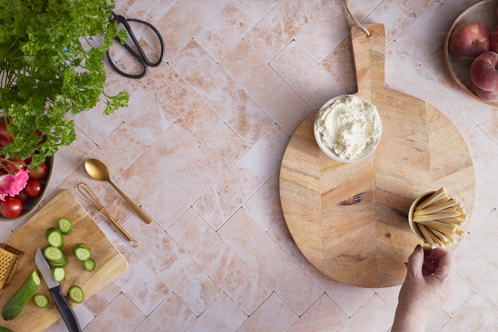 a wooden cutting board topped with a bowl of dip