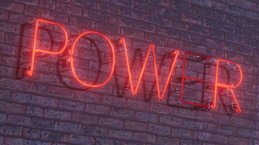 a brick wall with a neon sign that says power