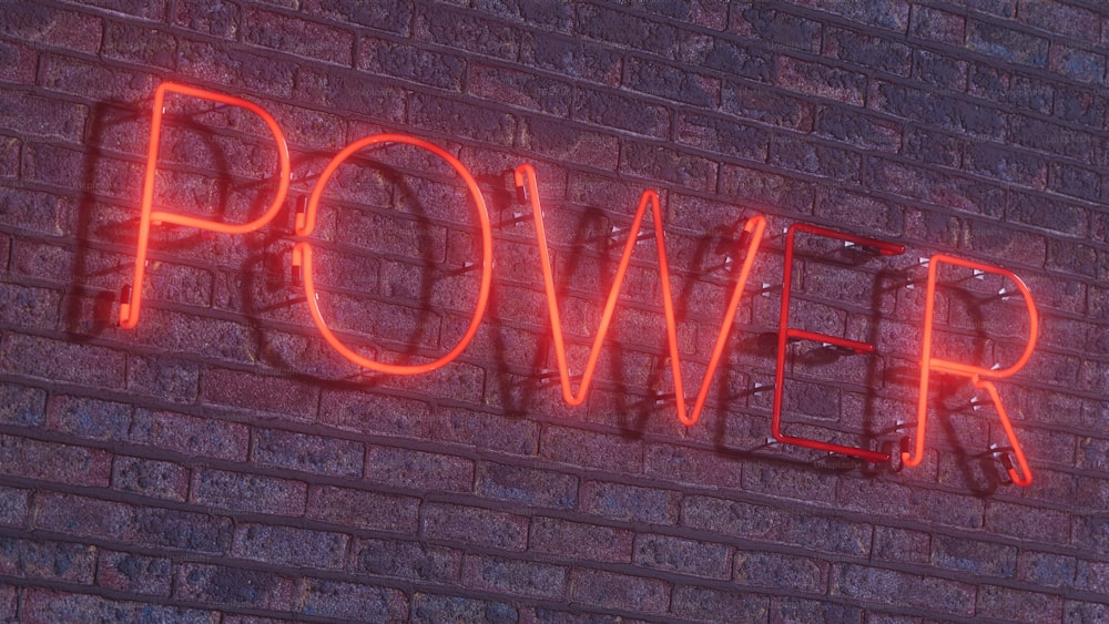 a brick wall with a neon sign that says power