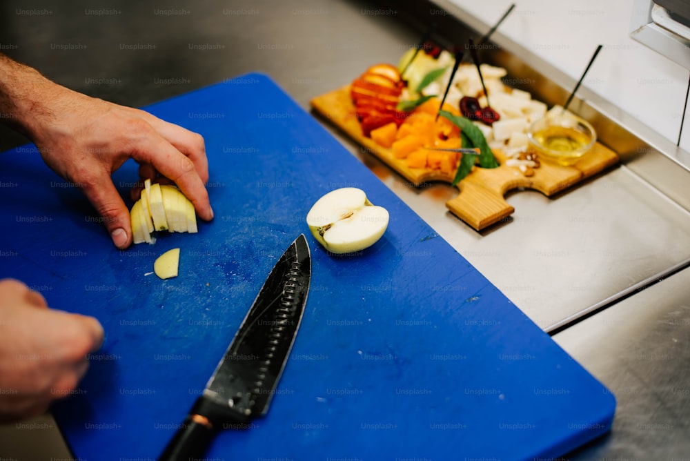 uma pessoa cortando maçãs em uma tábua de corte azul