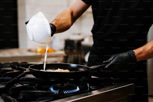 a person pouring milk into a skillet on top of a stove