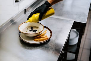 a person in black gloves is pouring something into a bowl