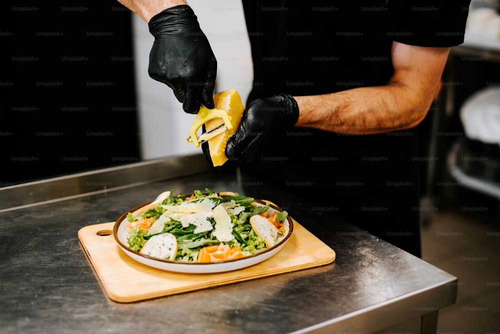 a person cutting a salad with a pair of black gloves