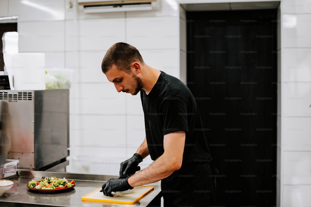 um homem em uma cozinha preparando comida em uma tábua de corte