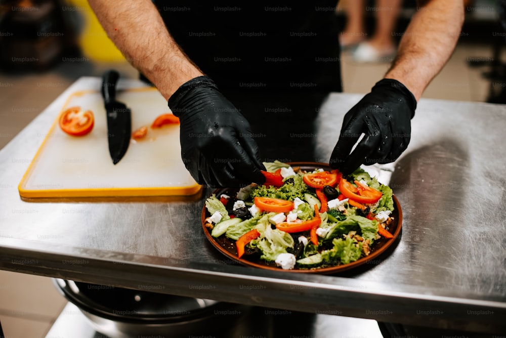 eine person in schwarzen handschuhen und schwarzen handschuhen, die einen salat zubereitet