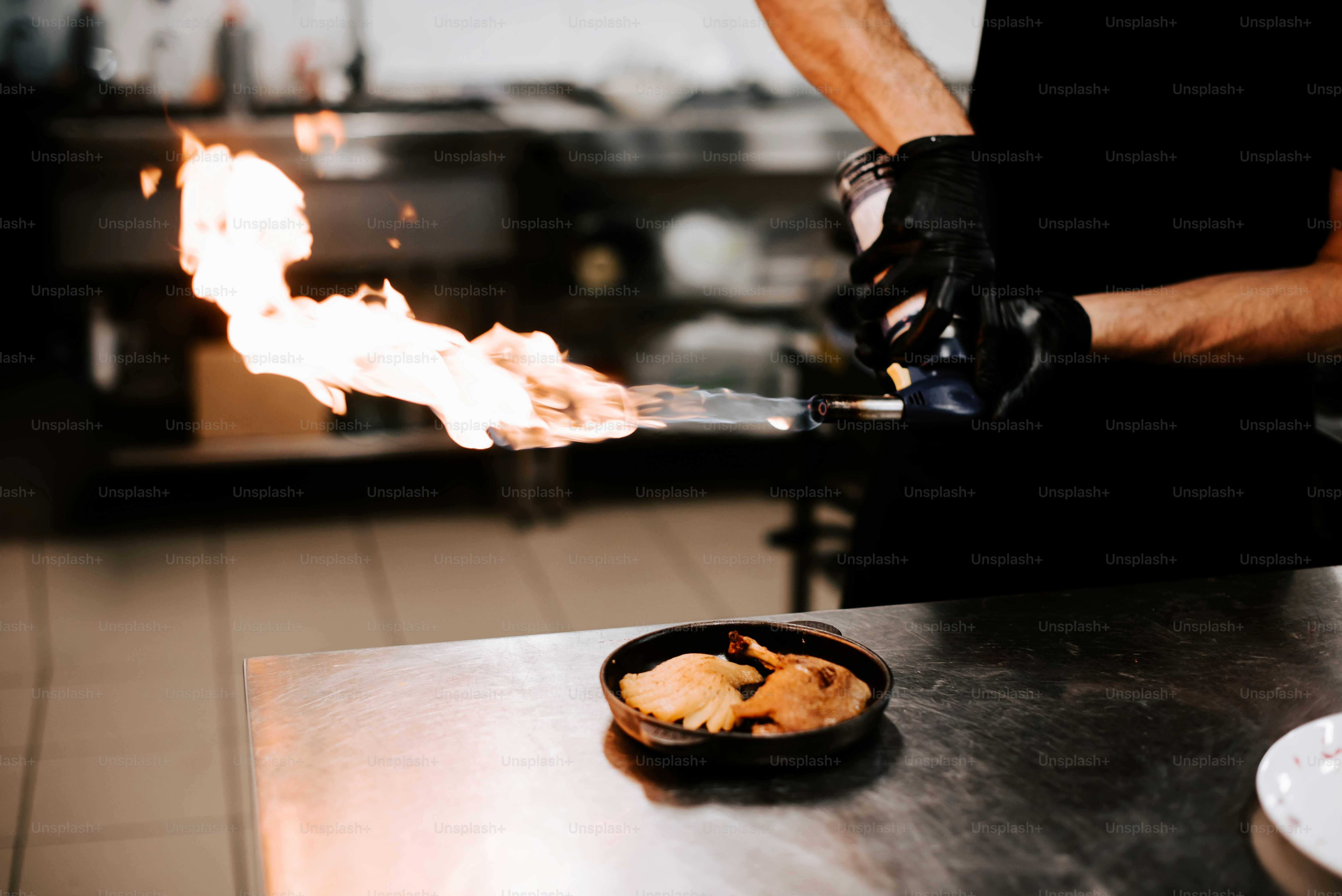 a person in a kitchen preparing food on a grill