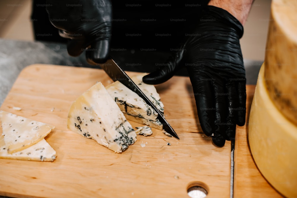 uma pessoa cortando queijo com uma faca em uma tábua de corte