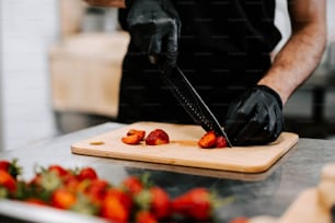 a person cutting strawberries on a cutting board