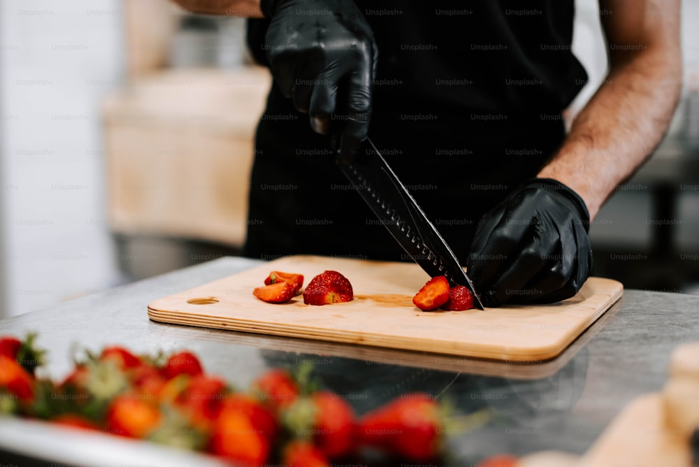 Una persona cortando fresas en una tabla de cortar