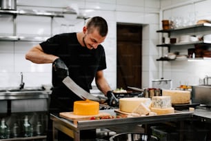 a man in a kitchen slicing cheese on a cutting board