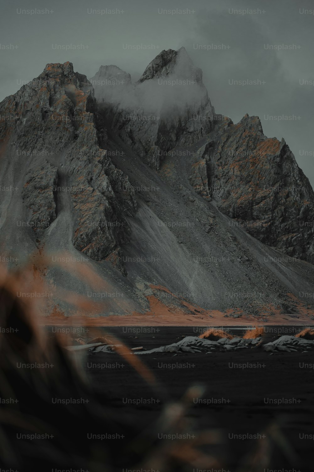 a mountain covered in clouds with a person standing in front of it