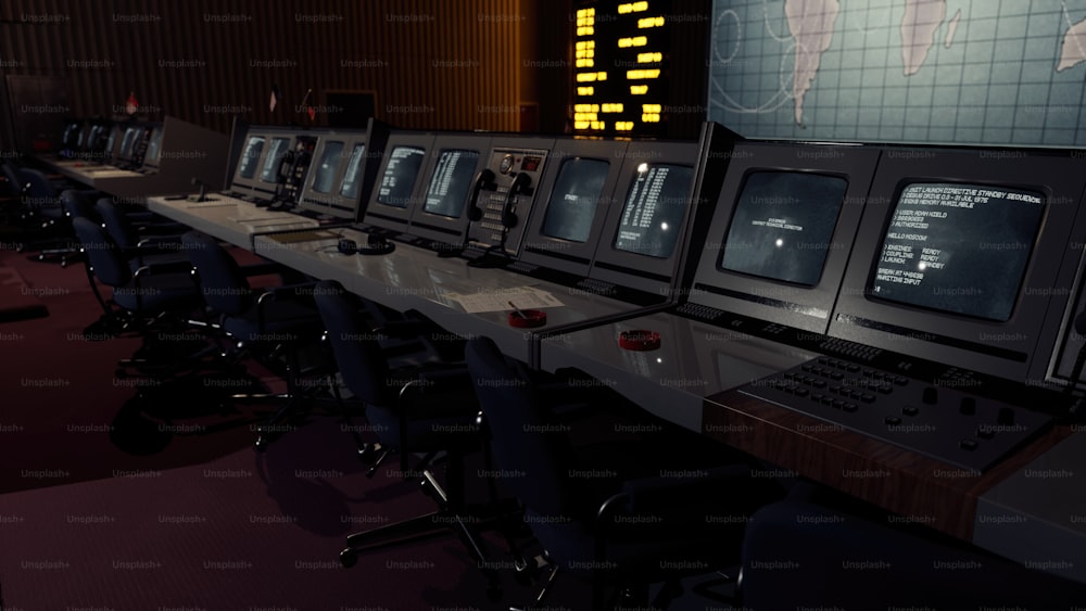 Una fila de monitores de computadora sentados encima de un escritorio