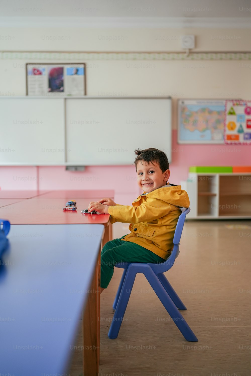 ein kleiner Junge, der an einem Tisch in einem Klassenzimmer sitzt