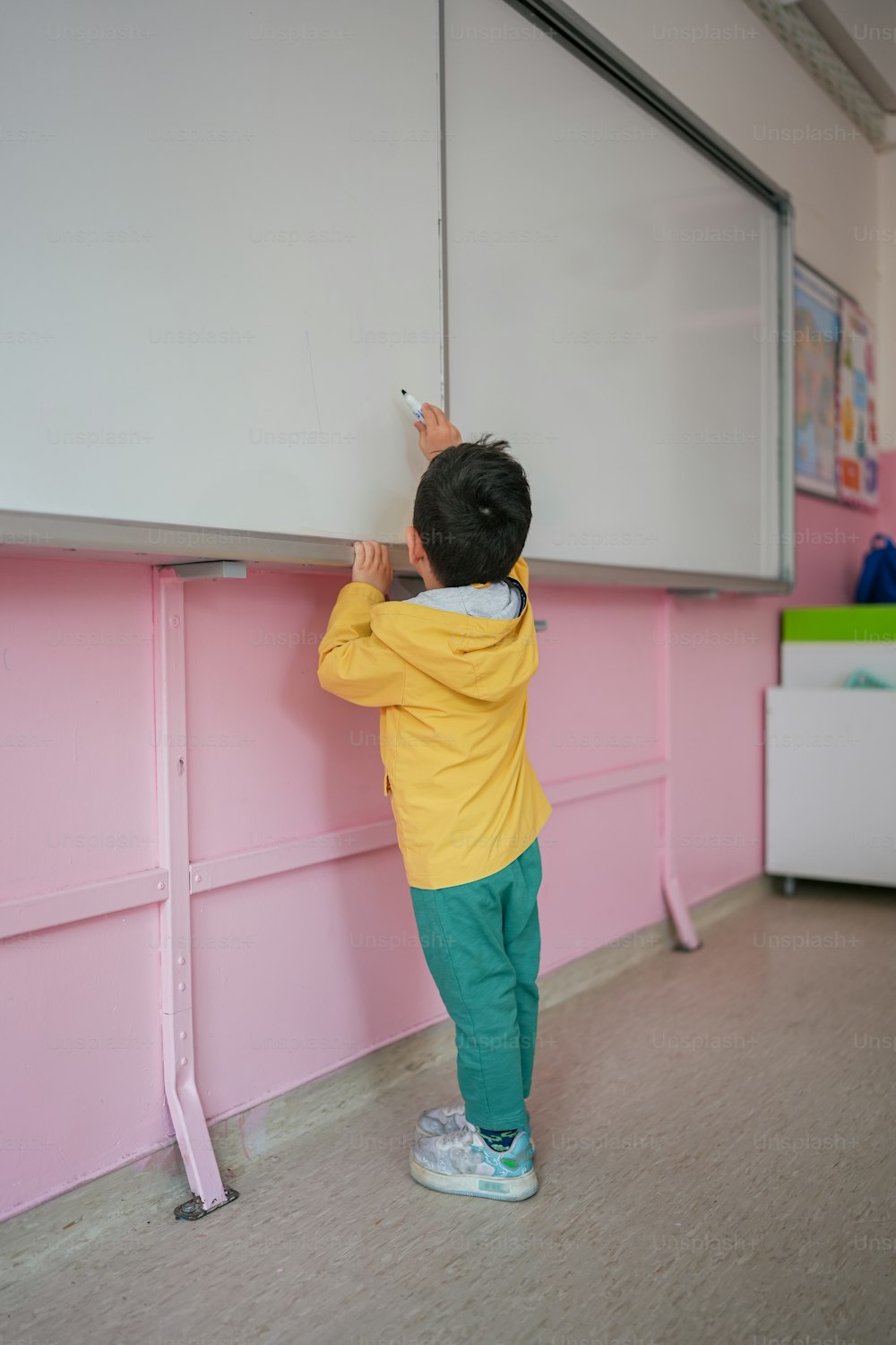 a little boy standing in front of a whiteboard