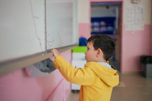 a little boy writing on a white board