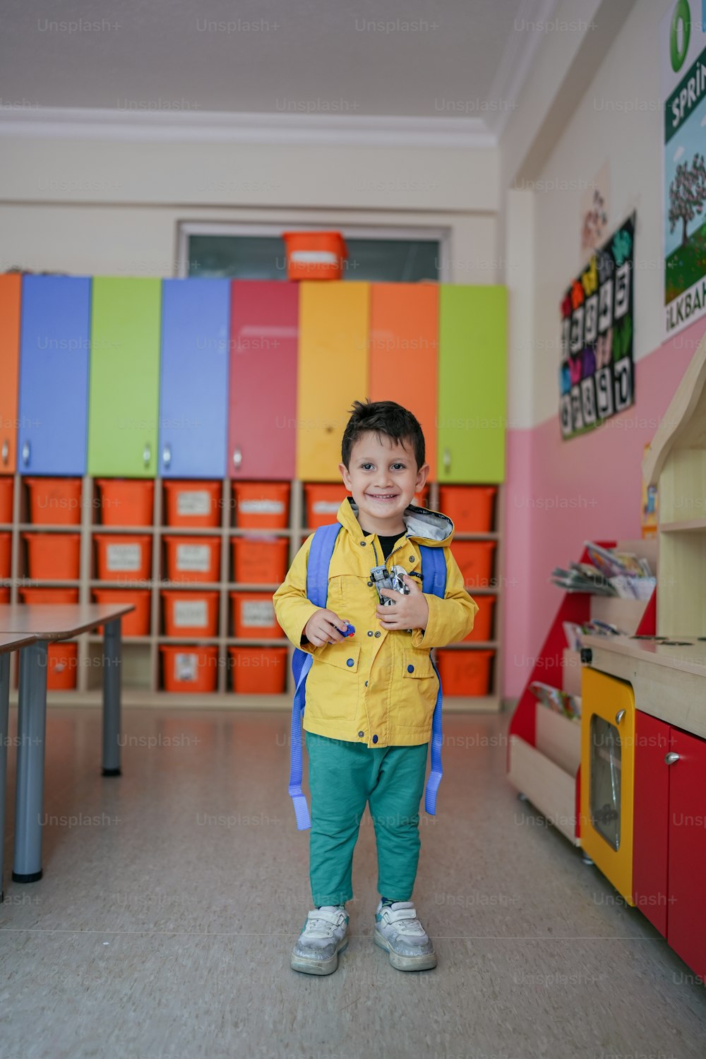 a young boy standing in front of a colorful wall
