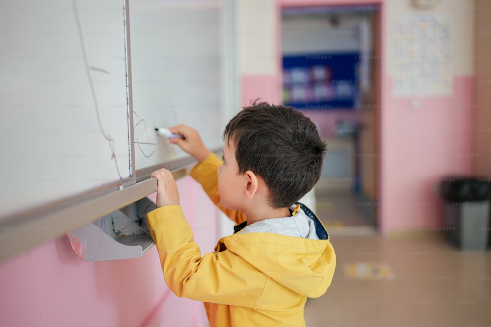 a little boy writing on a white board