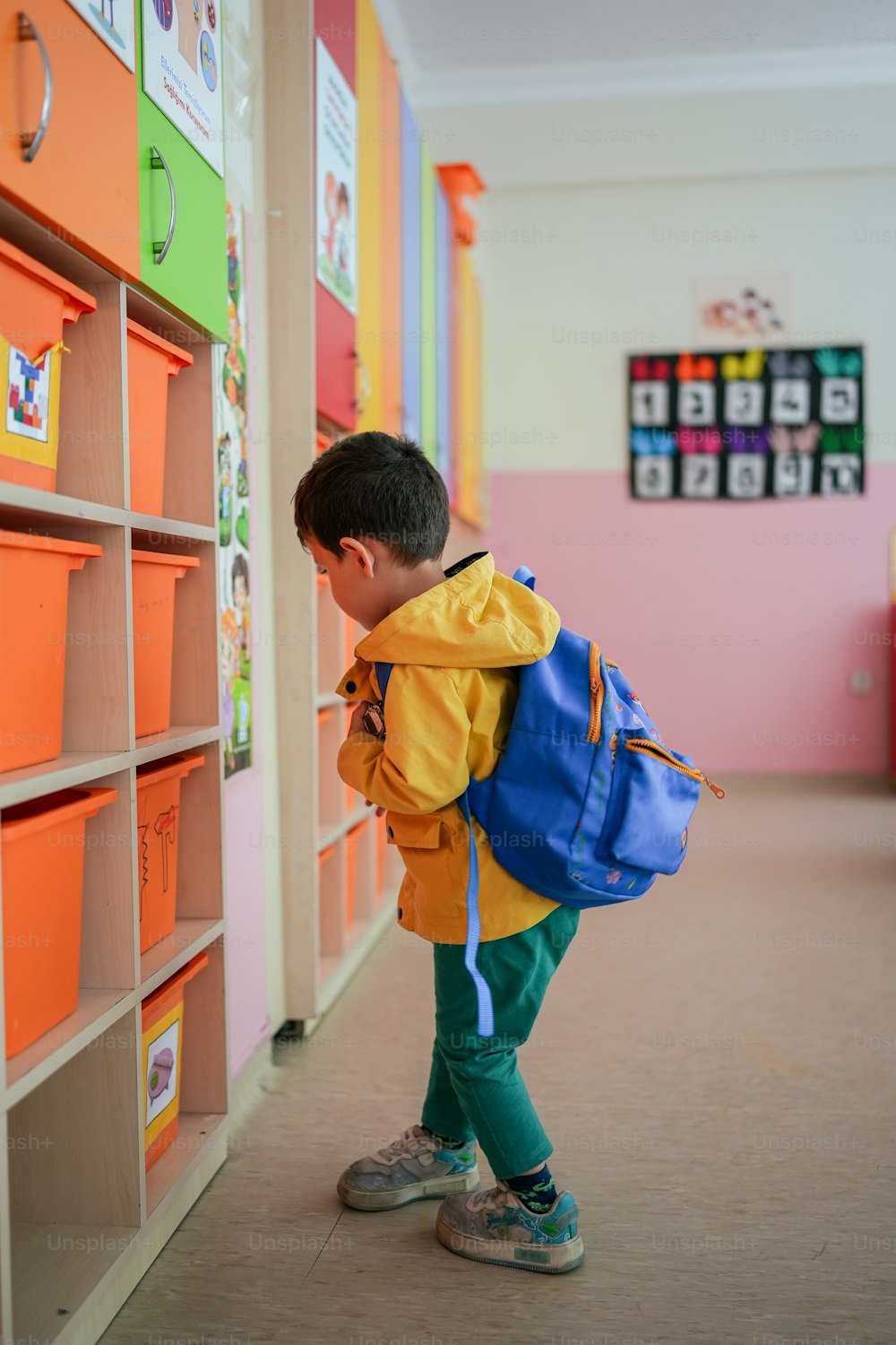 a little boy with a backpack looking at a book shelf