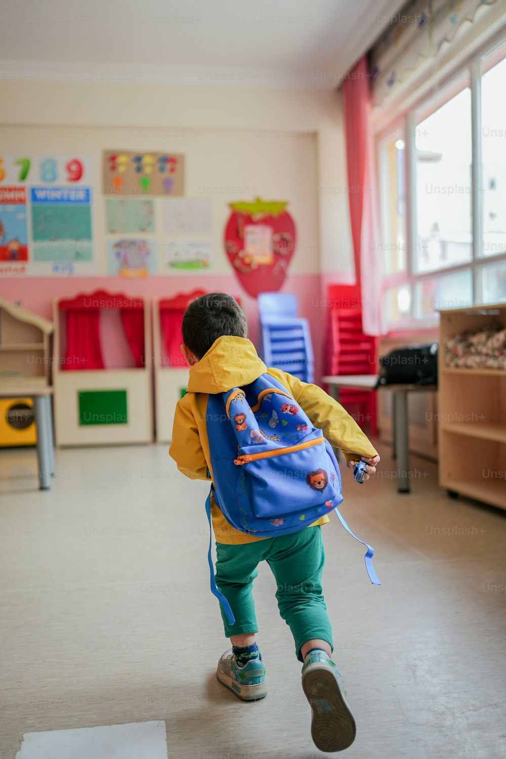 a little boy with a blue backpack running in a room