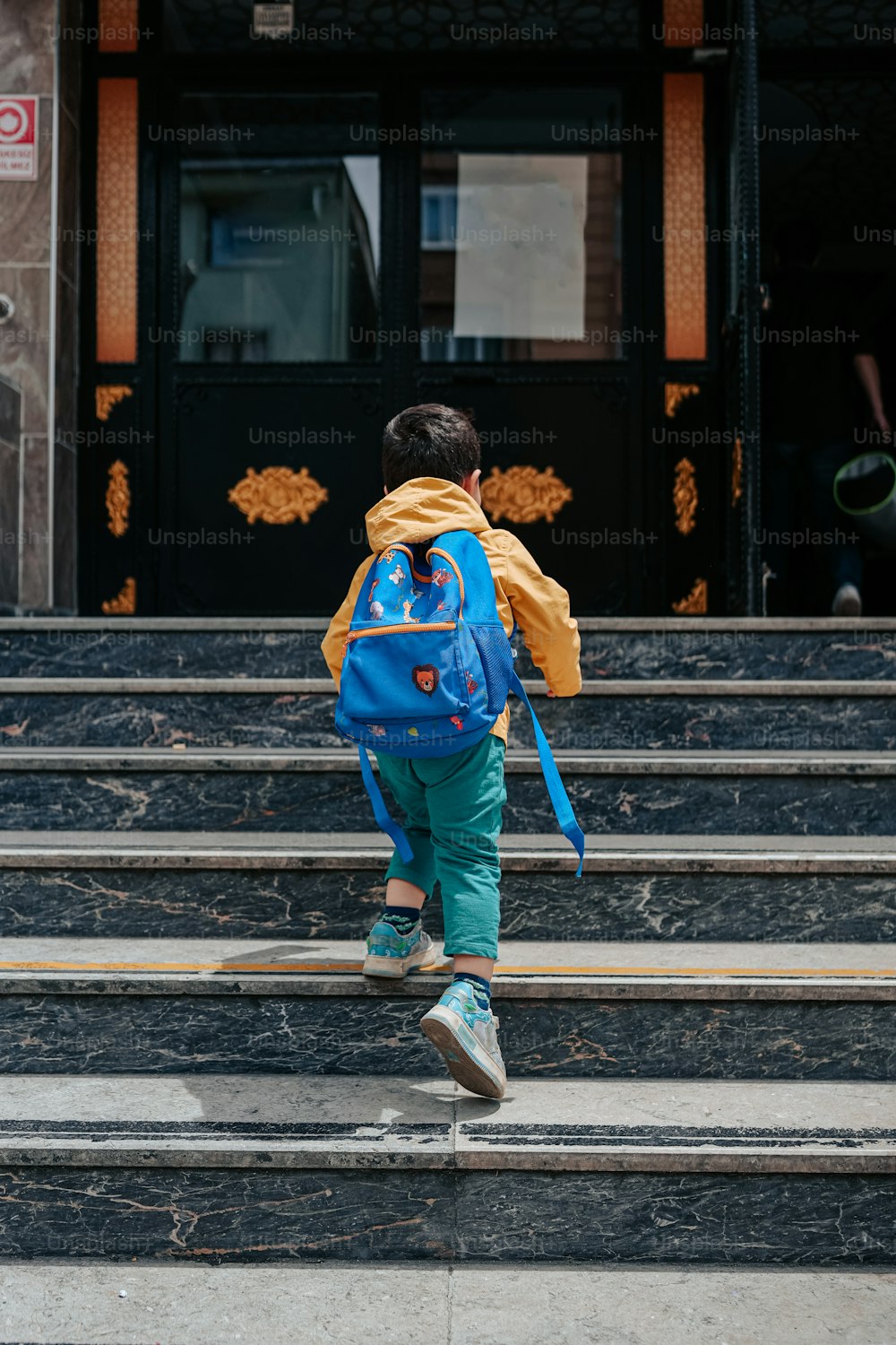 a little boy with a blue backpack walking up some steps